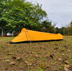 Yellow bivvy tent pitched side-on in open parkland