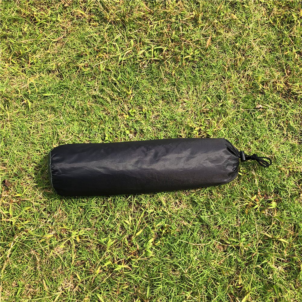The tent packed into its black stuff sack, lying on grass