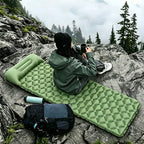A camper sitting on the inflatable mat on a rocky outcrop above the clouds