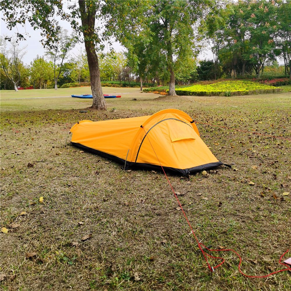 Yellow bivvy tent pitched in a park at low angle