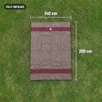 Blanket fully unfolded on grass, 140 cm by 200 cm, with a red stripe near each end